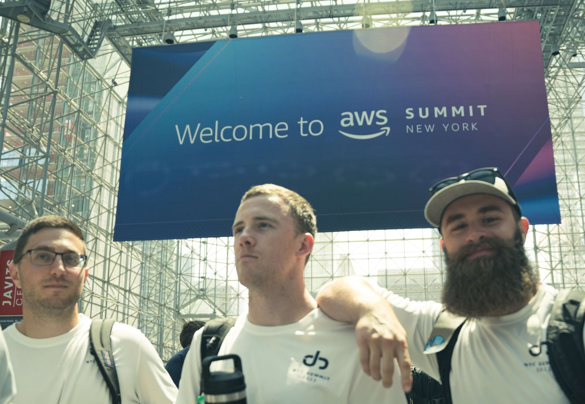 3 men in JG shirts under an AWS NYC Summit banner