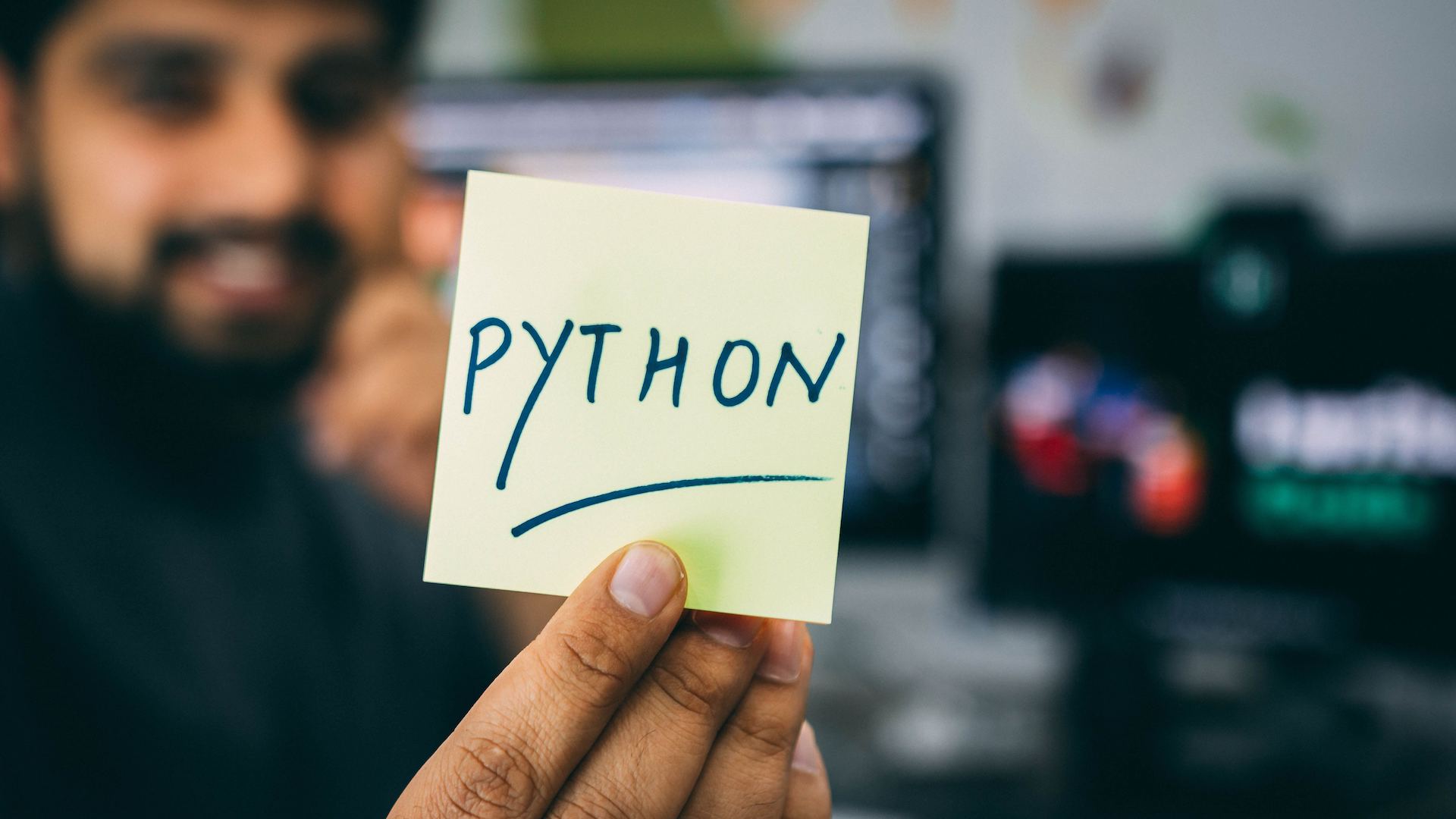 Man holding a sticky note that says Python